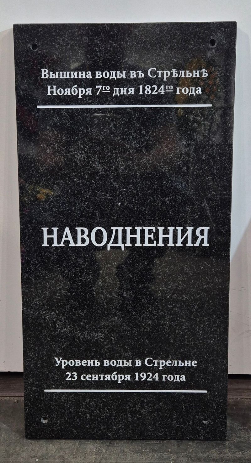 вертикальная мемориальная доска из чёрного гранита с гравировкой «НАВОДНЕНИЯ» и отметками уровня воды в Стрельне 1824 и 1924 годов, снята в помещении у стены